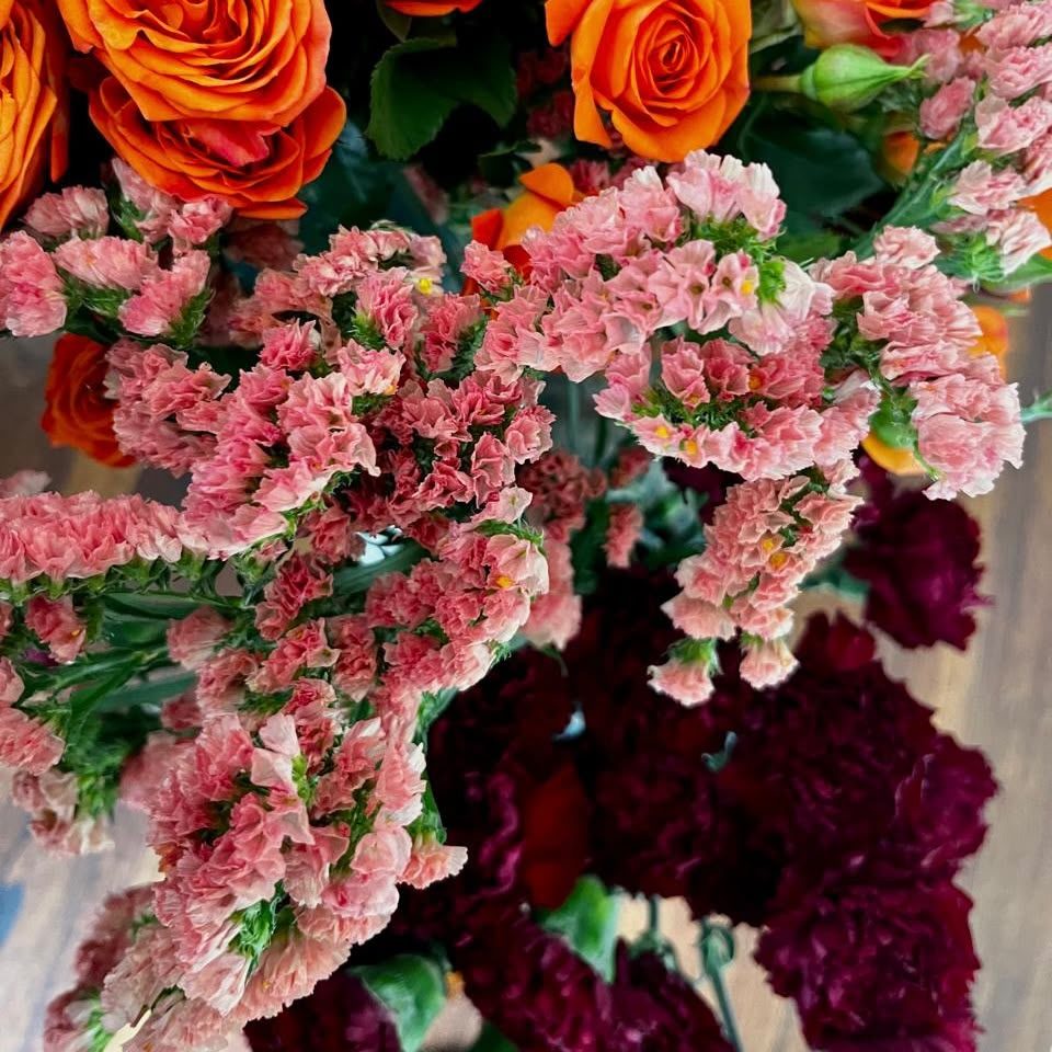 Jewel-toned roses and statice composition